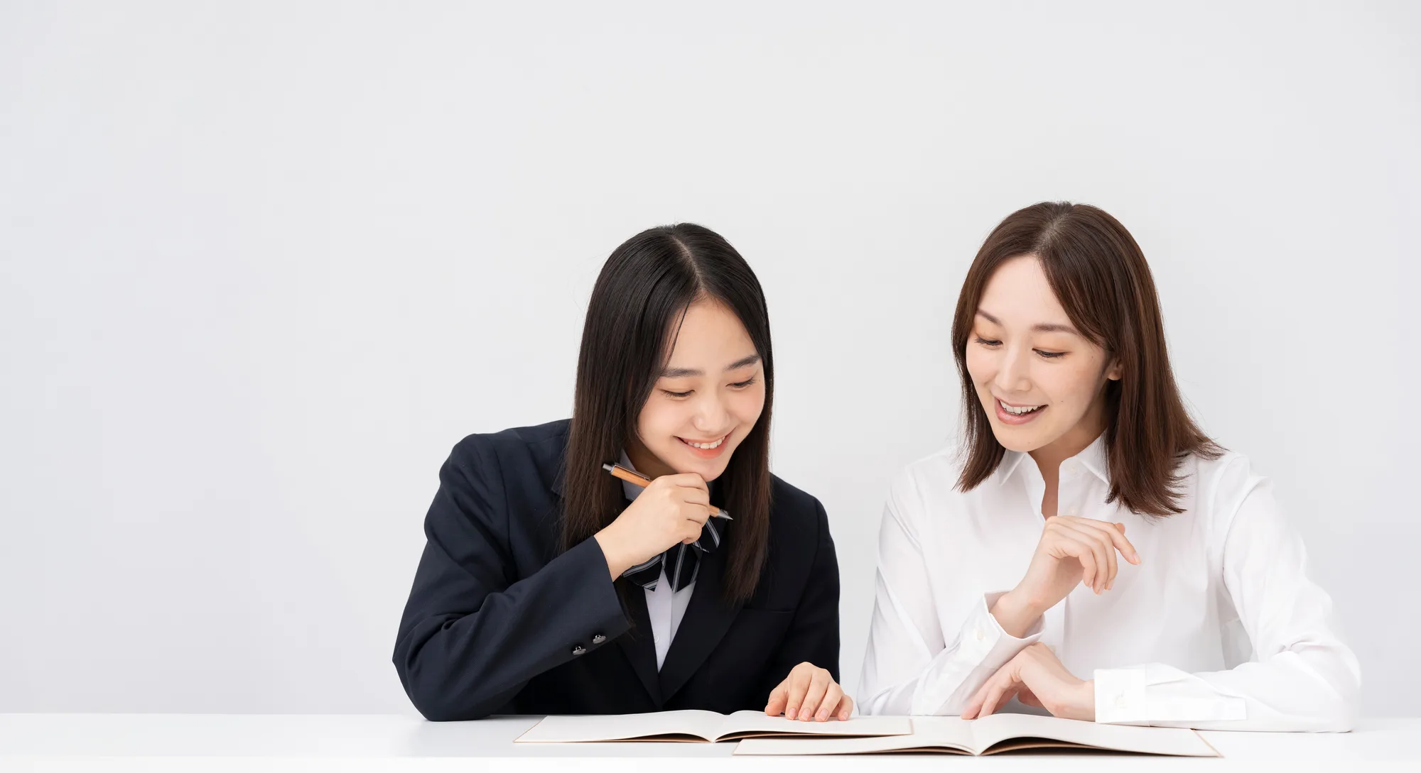 参考書を一緒に見る生徒と先生